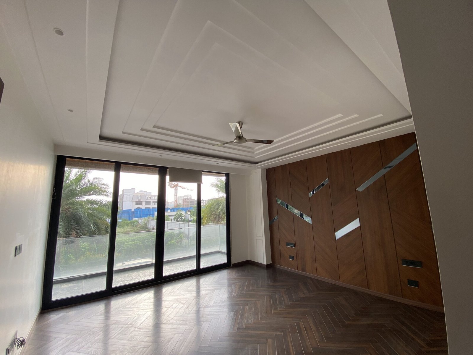 Master bedroom of a luxury builder floor in Emaar Emerald Hills Sector 65 Gurgaon featuring wooden flooring, designer wall paneling, and balcony